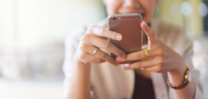 Woman using phone to schedule a garbage bin cleaning service online.
